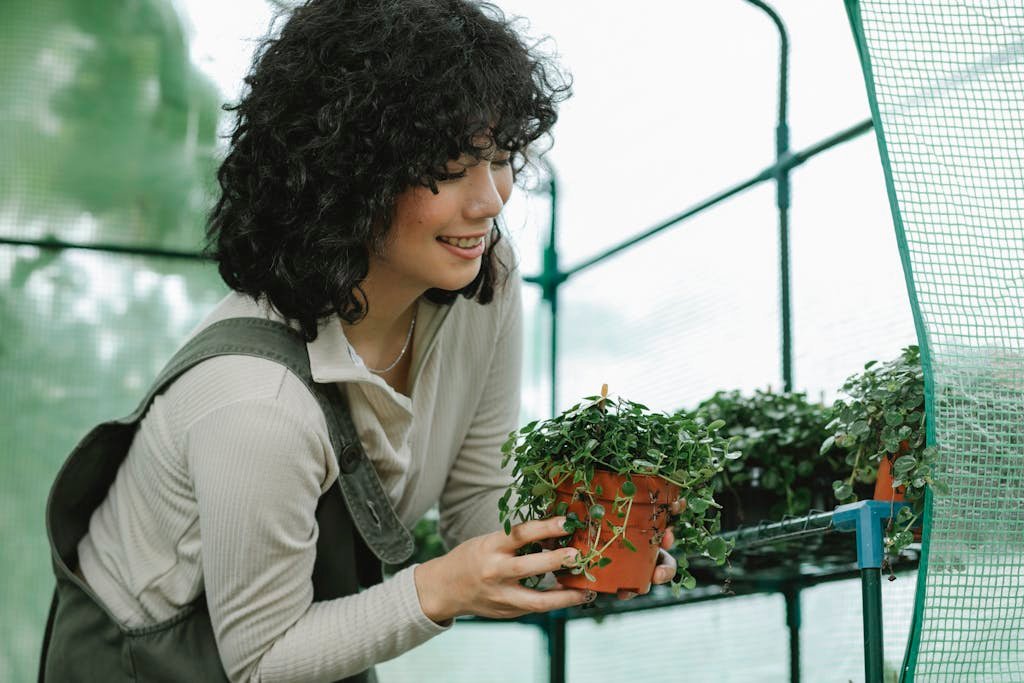 A smiling woman holding a green plant to demonstrate the link between Organic Foods and Health and Home Gardening ROI
