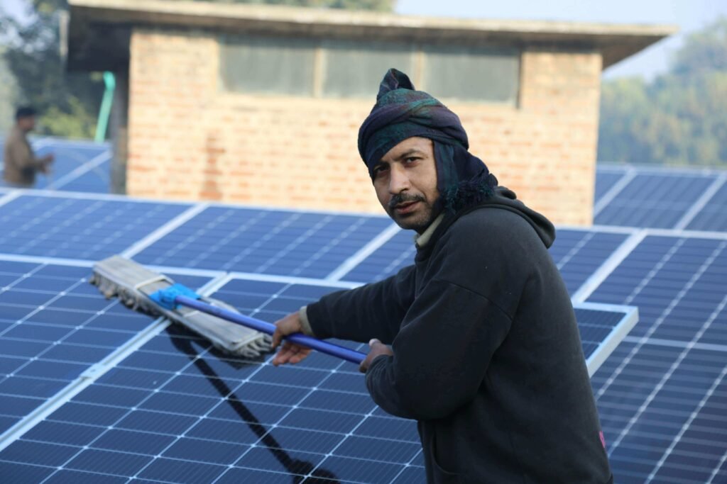 Manual solar panel cleaning process using specialized tools and safety gear